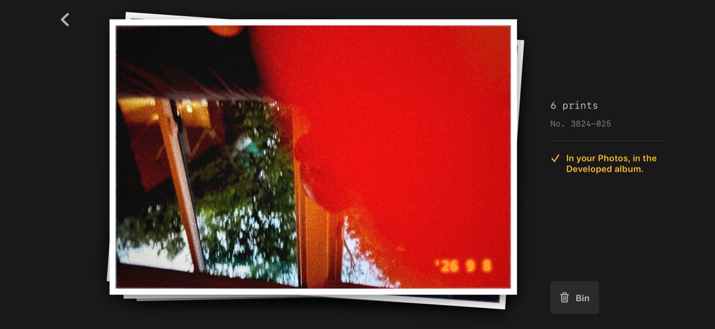 A pile of prints in Developed, the top one mostly swallowed by a red light leak, with the orange date stamp in the corner